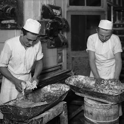 Christstollenb&auml;ckerei. Backstube. Dem Stollenteigs werden die Zutaten (Mandeln, Rosinen, Zitronat, etc.) mit der Hand beigemischt